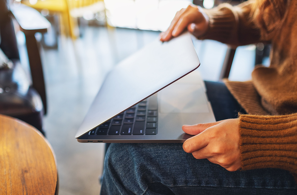 Sitzende Person öffnet Laptop